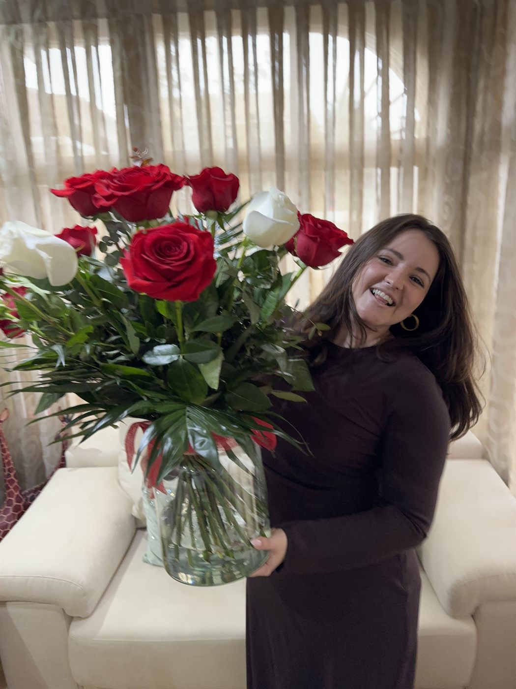 Macarena riéndose mientras sostiene el jarrón con las rosas rojas y blancas