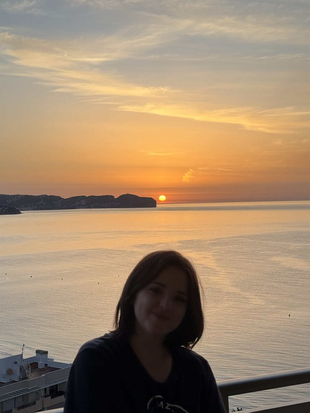 Macarena en una terraza con el sol poniéndose sobre el mar