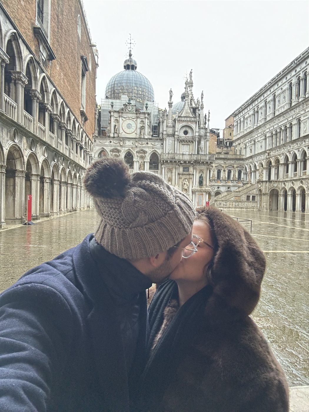 Un beso en el patio del Palacio Ducal de Venecia, con el suelo mojado por la lluvia
